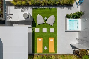 Una terraza en la azotea con césped, sillones de descanso, una piscina y una fuente.