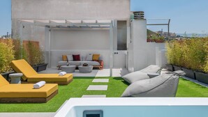 En tagterrasse med pool, liggestole, sofa og pergola.