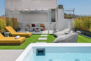 Eine Dachterrasse mit Pool, Liegestühlen, einer Sitzecke und einer Pergola.