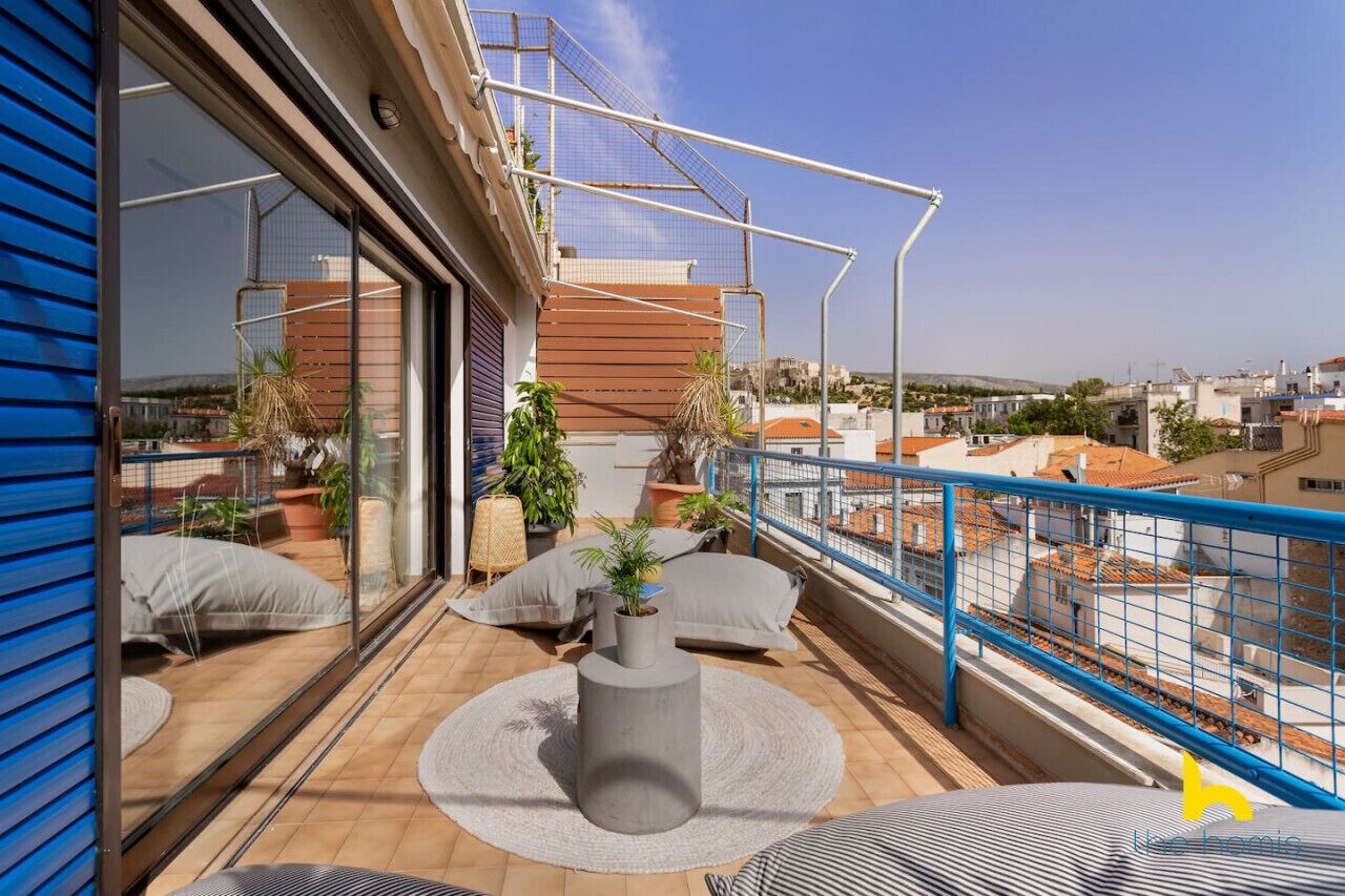 Un balcon avec vue sur la ville, une table ronde et des plantes en pot.