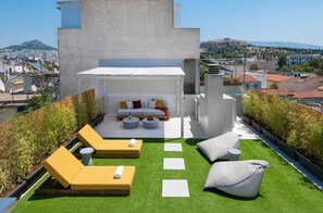 A rooftop terrace with a seating area, artificial grass, and a view of the cityscape. - Penthouse With Magical Acropolis View & Jacuzzi! (Athina)