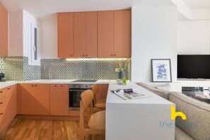 Eine moderne Küche mit Holzausstattung, einem eingebauten Ofen und einem Essbereich mit einer weißen Kücheninsel und Stühlen.