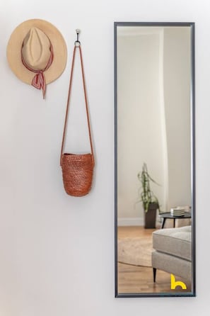 A wall-mounted mirror with a reflection of a room, a hat, and a woven bag. - Enigmatic Romantic Nest w/Fireplace Near Acropolis (Athina)