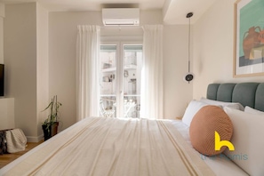A bedroom with a bed, a potted plant, a ceiling fan, and a window with curtains. - Charming Koukaki Studio Cozy & Vibrant Retreat! (Athina)