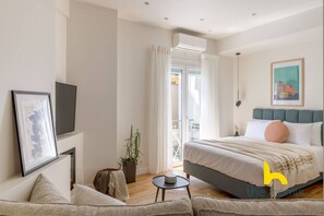 Une chambre à coucher moderne avec un lit, une petite table, une plante et un tableau encadré au mur.