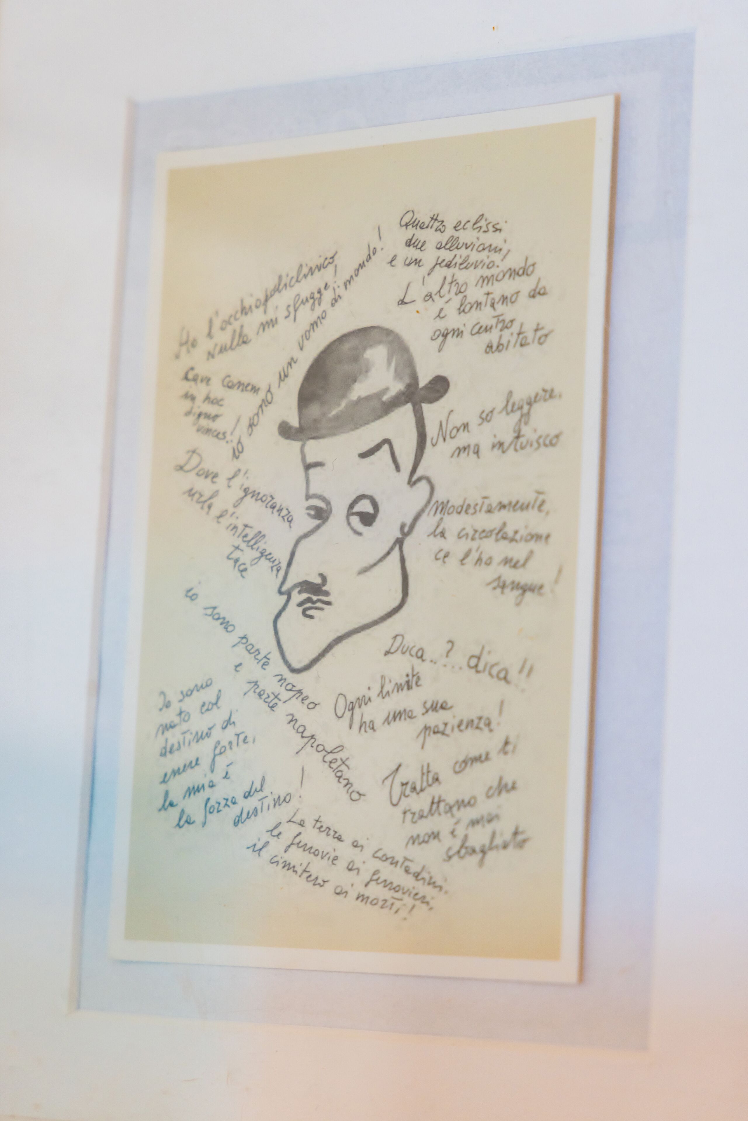 A framed handwritten note with a drawing of a man's face and text in Italian.