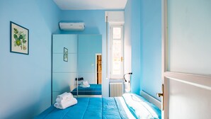 Un dormitorio con cama, armario, radiador y ventana.