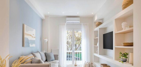 A modern living room with a sofa, a flat-screen TV, and a bookshelf. - Koukaki Elegance Athenian Retreat near Acropolis! (Athina)