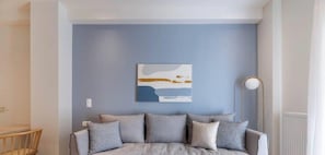 A room with a light blue wall, a gray sofa with multiple cushions, a white radiator, and a modern floor lamp. - Koukaki Elegance Athenian Retreat near Acropolis! (Athina)