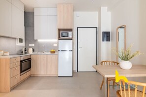 Een moderne keuken met houten kastjes, een magnetron, een koelkast en een eettafel met stoelen.