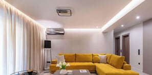 A modern living room with a yellow sofa, a glass coffee table, and a floor lamp.