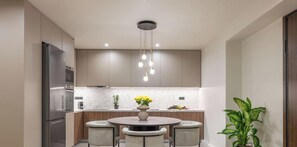 Una cocina moderna con una isla central, electrodomésticos de acero inoxidable e iluminación colgante.
