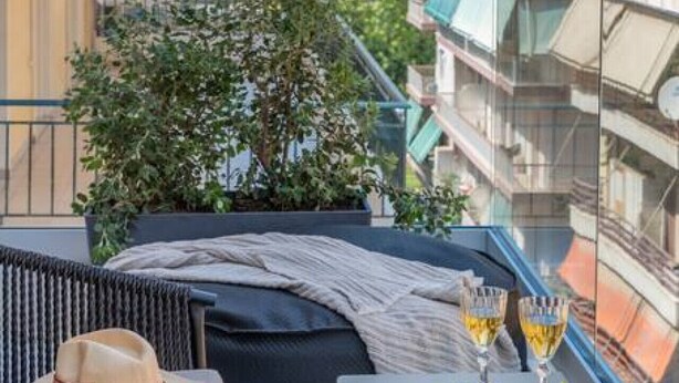 A balcony with a table set for two, a potted plant, and a view of the cityscape. - Premium Retreat w/ Patio, Parking & Acropolis View (Athina)
