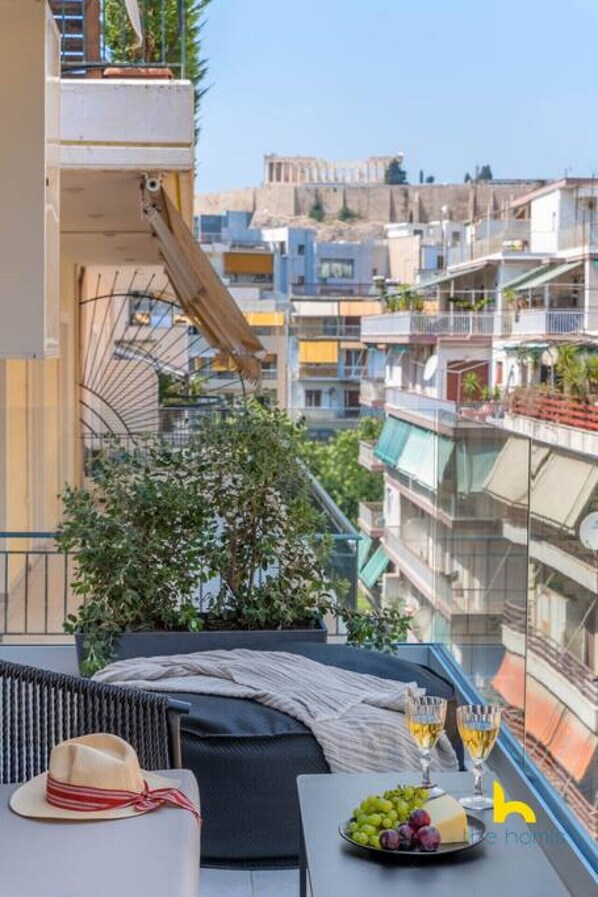 Un balcón con una mesa para dos, una planta en maceta y vistas de la ciudad.