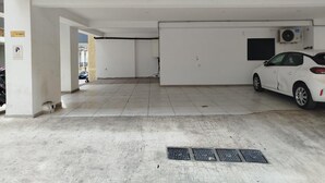 A parking garage with a white car parked, concrete floors, and a ventilation unit on the wall. - Premium Retreat w/ Patio, Parking & Acropolis View (Athina)