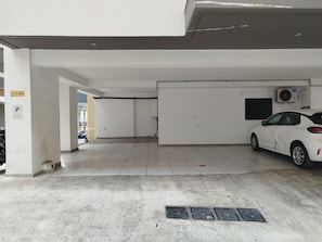 A parking garage with a white car parked, concrete floors, and a ventilation unit on the wall. - Premium Retreat w/ Patio, Parking & Acropolis View (Athina)