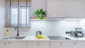 A modern kitchen with a sink, a kettle, a coffee maker, and a cutting board with lemons. - 50 Shades of Athens, Kingsize Suite with Jacuzzi! (Athina)
