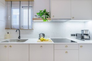 A modern kitchen with a sink, a kettle, a coffee maker, and a cutting board with lemons. - 50 Shades of Athens, Kingsize Suite with Jacuzzi! (Athina)