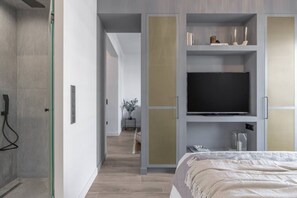 Une chambre d’hôtel moderne dotée d’un grand lit, d’une télévision et d’un dressing avec un miroir.