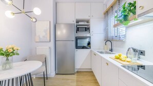 A modern kitchen with white cabinetry, a stainless steel refrigerator, a microwave, and a sink with a cutting board and lemons. - 50 Shades of Athens, Kingsize Suite with Jacuzzi! (Athina)