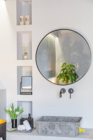 A bathroom with a round mirror, a rectangular sink, and a shelf with decorative items. - 50 Shades of Athens, Kingsize suite with Jacuzzi! (Athina)