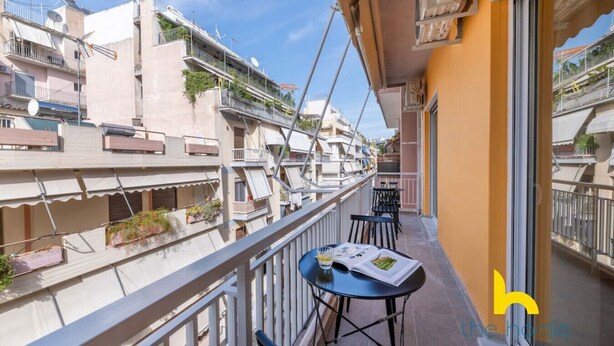 Un balcón con una mesa y sillas, con vistas a una zona residencial con múltiples balcones y edificios.