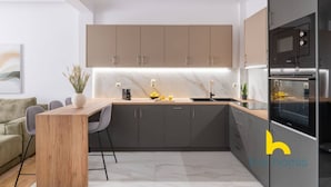 Una cocina moderna con encimera de mármol, armarios grises y horno empotrado.