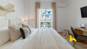 Una habitación de hotel con una cama grande, un escritorio, una silla, un televisor y una ventana con cortinas.