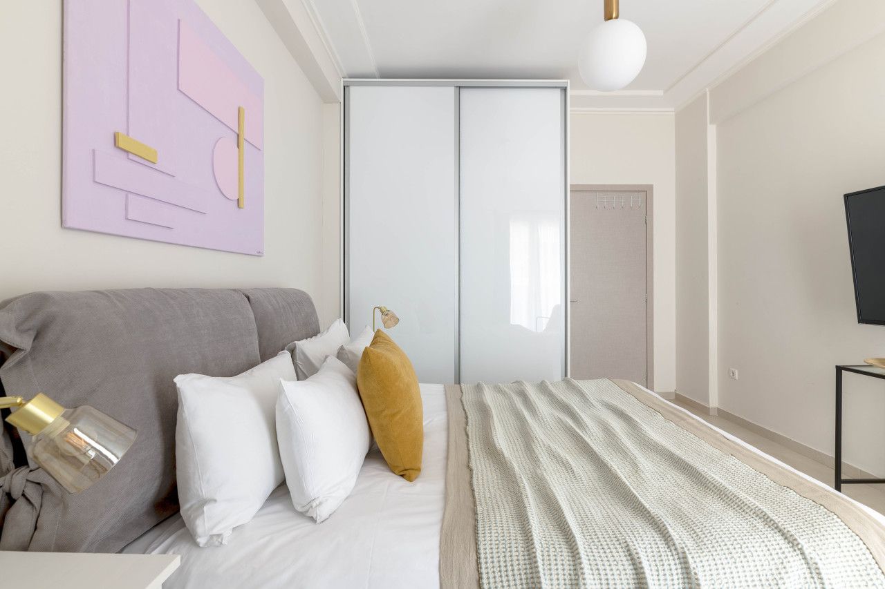 A bedroom with a bed, pillows, a bedside lamp, a wardrobe, and a television.