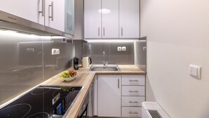 Ett modernt kök med vitvaror i rostfritt stål, vita köksskåp och en bänkskiva i trä.