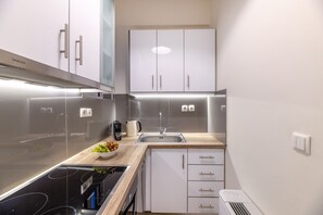 Cozinha moderna com eletrodomésticos de aço inoxidável, armários brancos e bancada de madeira.