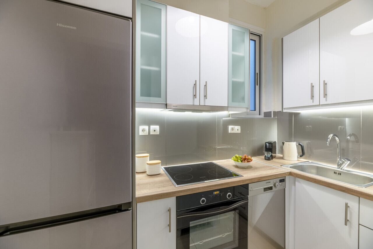 Une cuisine moderne dotée d’appareils électroménagers en acier inoxydable, de meubles blancs et d’un four encastré.