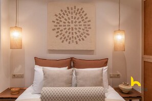 A hotel room with a bed, two wall-mounted lamps, a decorative wall piece, and a small table with a bowl. - Acropolis Zen Oasis romantic retreat in Koukaki! (Athina)