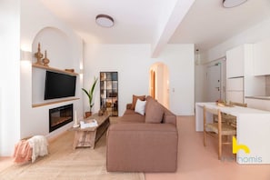 A modern living room with a flat-screen TV, fireplace, sofa, and dining area. - Acropolis Zen Oasis Romantic Retreat in Koukaki! (Athina)