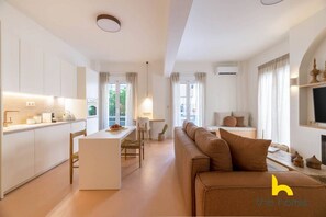 A modern living room with a sofa, a dining area, and a kitchen. - Acropolis Zen Oasis romantic retreat in Koukaki! (Athina)