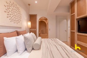Ein modernes Schlafzimmer mit Bett, Kissen, einem Wandbild, einem Fernseher und einem Holzschrank.