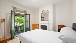 Un dormitorio con una cama, un aparador, un espejo y una chimenea.