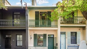 Un hilera de casas urbanas con balcones, una puerta verde y una puerta azul.