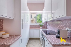 Eine moderne Küche mit weißen Schränken, Granit Arbeitsplatten und einem Fenster mit Blick auf Grünflächen.
