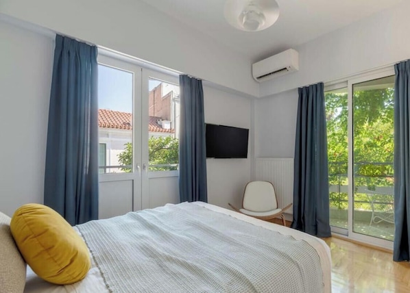Ein Hotelzimmer mit Bett, Sessel, Fernseher und einer Schiebetür zum Außenbereich.