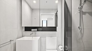 A modern bathroom with a white sink, toilet, and shower. - South Yarra Stay with Balcony Views (South Yarra)