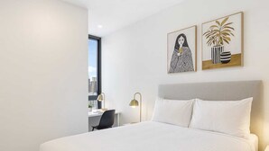 A hotel room with a large bed, a desk with a chair, and two framed artworks on the wall. - South Yarra Stay with Balcony Views (South Yarra)