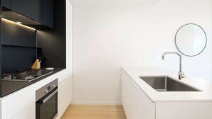 A modern kitchen with a black range hood, a stainless steel sink, and a round mirror. - South Yarra Stay with Balcony Views (South Yarra)