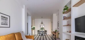 Un salon moderne avec un canapé, un coin repas comprenant une table et des chaises, et un téléviseur fixé au mur.