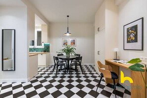 Une cuisine moderne avec un carrelage à motifs, un coin repas doté d’une table ronde et un bureau agrémenté d’une plante.