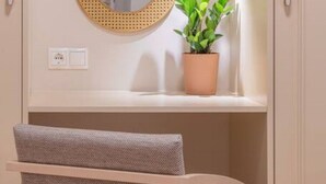 Un baño con un espejo redondo, una planta en maceta y un banco.