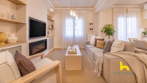Una sala de estar moderna con televisor de pantalla plana, chimenea, un conjunto de sofás y una mesa de centro.