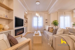 Ein modernes Wohnzimmer mit Flachbildfernseher, Kamin, Sofagarnitur und Couchtisch.