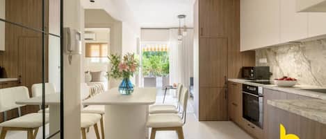A modern kitchen with a marble countertop, wooden cabinets, and a dining area with a white table and chairs.
