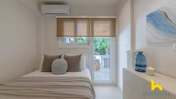 Une chambre à coucher avec un lit, un radiateur, une fenêtre avec des stores et une vue sur l’extérieur.